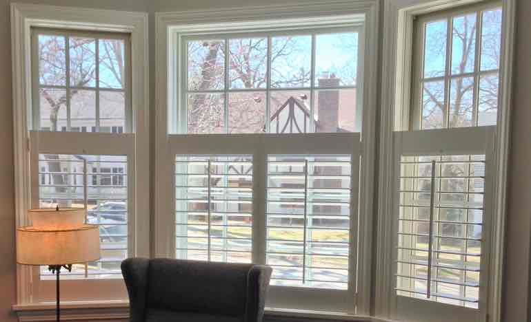 Bottom half plantation shutters in living room bay window.